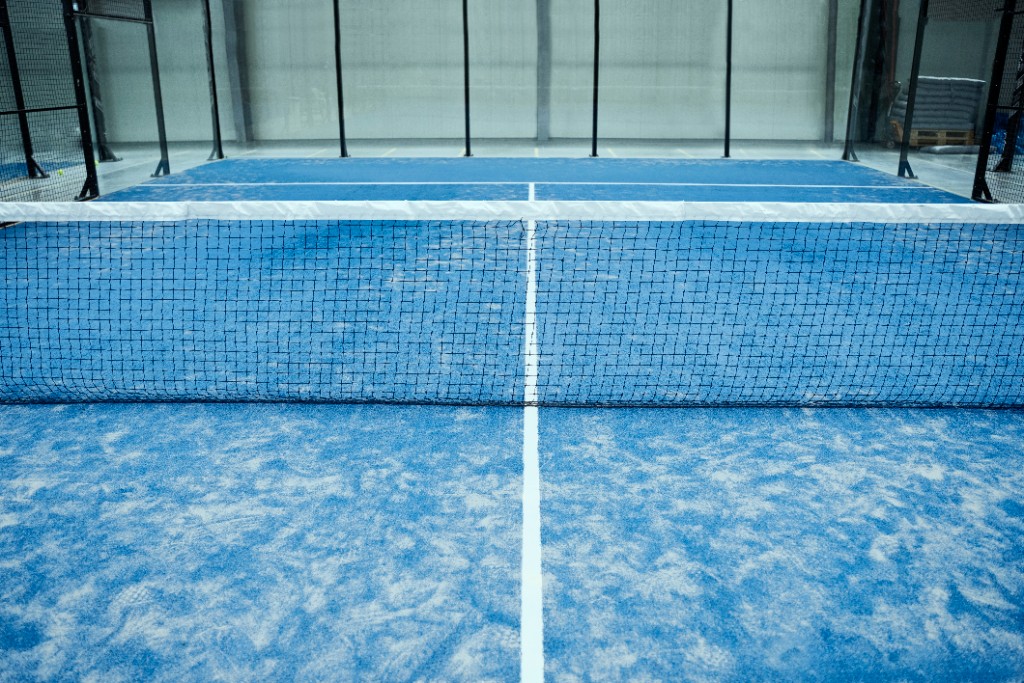 Terrain de padel bleu avec filet vu de près après nettoyage